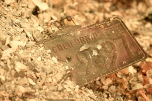 A California license plate is seen partially buried in a pile of ash.