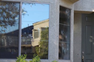 Bullet holes mark the windows of a house that was hit by gunfire