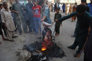 Pakistani protesters burn a poster image of Christian woman Asia Bibi, who has spent eight-years on death row accused of blasphemy and acquitted by a Supreme Court, in Hyderabad, Pakistan.