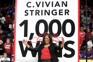 C. Vivian Stringer celebrates her 1,000th win in front of a commemorative banner