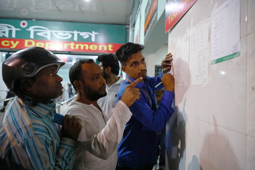 Men look at a list of people who were injured in a fire.