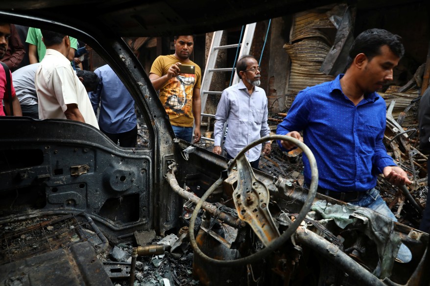 A man takes a picture outside a burnt warehouse in Dhaka, Bangladesh, February 21, 2019.