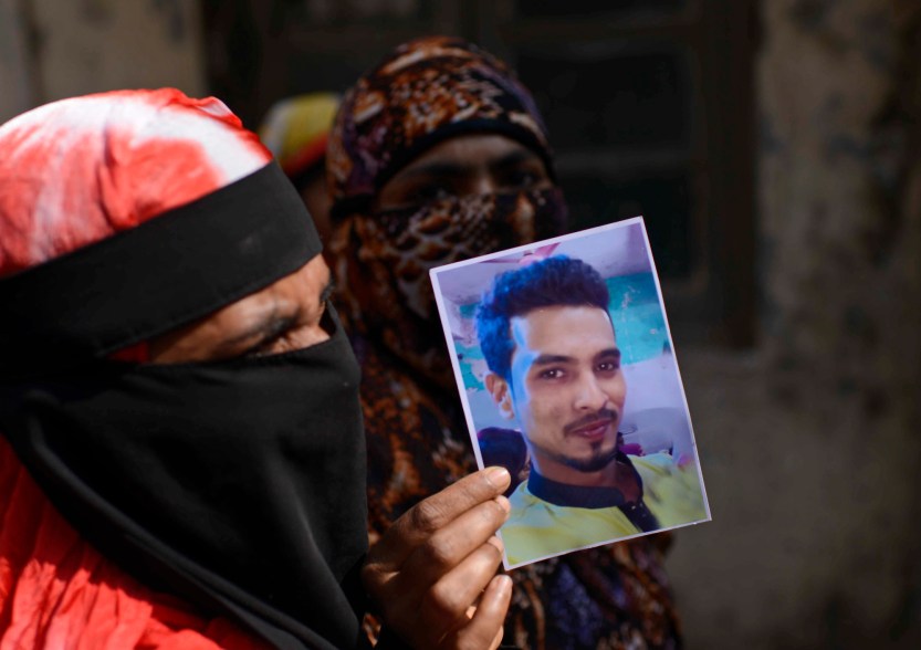 A woman displays a photograph of a relative who died in a fire, outside a morgue in Dhaka, Bangladesh, Thursday, Feb. 21, 2019.