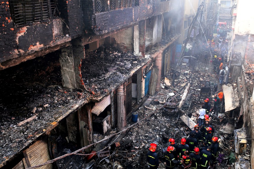 Locals and firefighters gather around buildings that caught fire late Wednesday in Dhaka, Bangladesh, Thursday, Feb. 21, 2019.