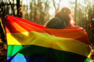 Two embracing same-sex marriage girls with rainbow flag