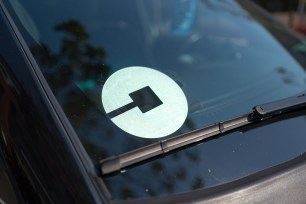 Logo for car-sharing company Uber on the passenger side windshield of a vehicle.
