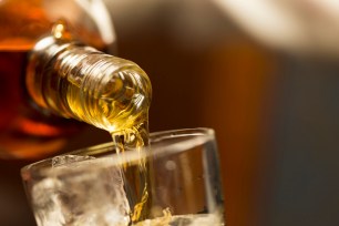 Whiskey being poured from a bottle into a glass.