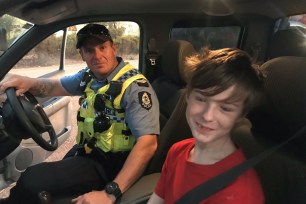 A 12-year-old boy sits next to Dalwallinu Police officer S/C Smith after he drove across paddocks to escape the fire in Mogumber, Australia