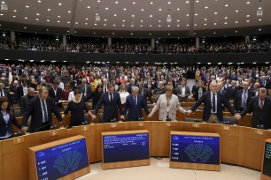 The European Parliament holding hands and singing after the vote.