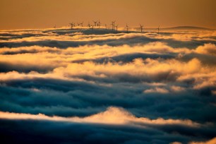 Wind turbines stand on a hill and are surrounded by fog and clouds in the Taunus region near Frankfurt, Germany.