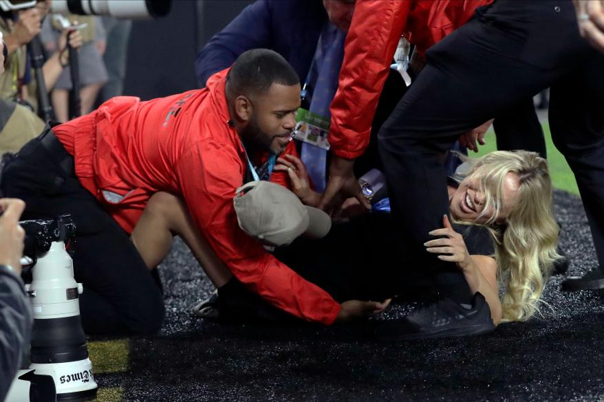 Security guards tackling a woman who tried to get on the field at the Super Bowl.