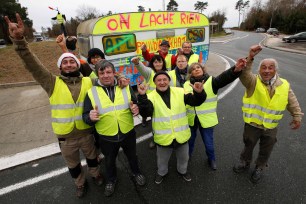 Protesters wearing yellow vests pose in front of a trailer with the slogan "We give up nothing" as they occupied a roundabout as part of the "yellow vests" protest in Cissac-Medoc, France (December 2018).