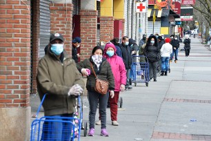 Queens residents wearing masks and protective gear wait in a line for two hours trying to get into the Food Bazaar.