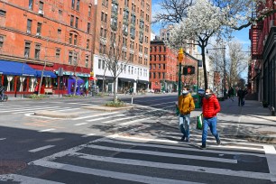 People wearing masks walk down a New York City street