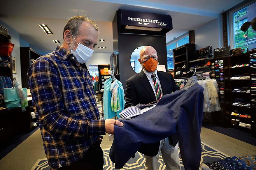 Peter Elliot, owner of the Upper East Side clothing store "Peter Elliot" in NYC, assists a customer.