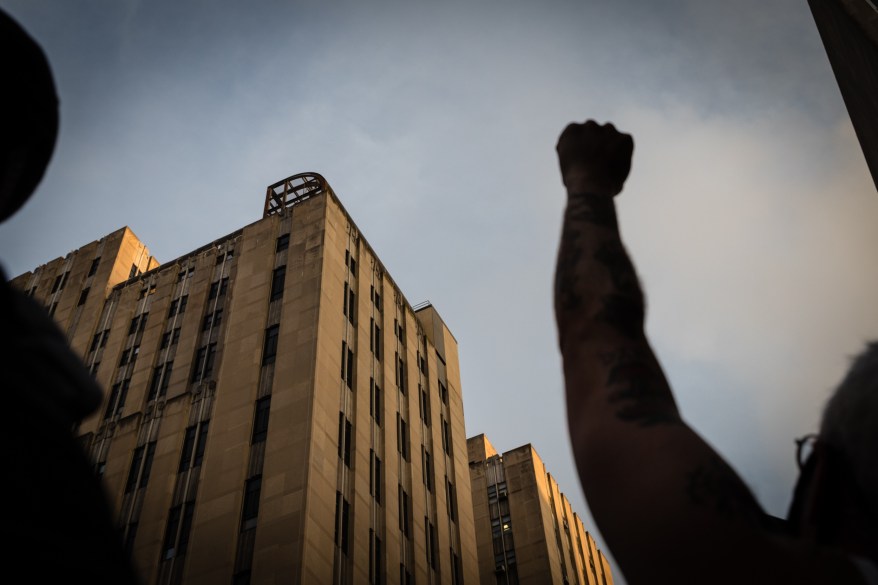 An inmate looks down from the caged rooftop recreation area as protesters stop outside the Manhattan Detention Center on Center Street and cheer in solidarity with people being held at the facility in downtown, Manhattan on Thursday June 11, 2020 in New York City.