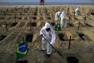 Activists of the NGO Rio de Paz wear protective gear to dig graves on Copacabana beach to symbolize the dead from coronavirus during a demonstration in Rio de Janeiro, Brazil.