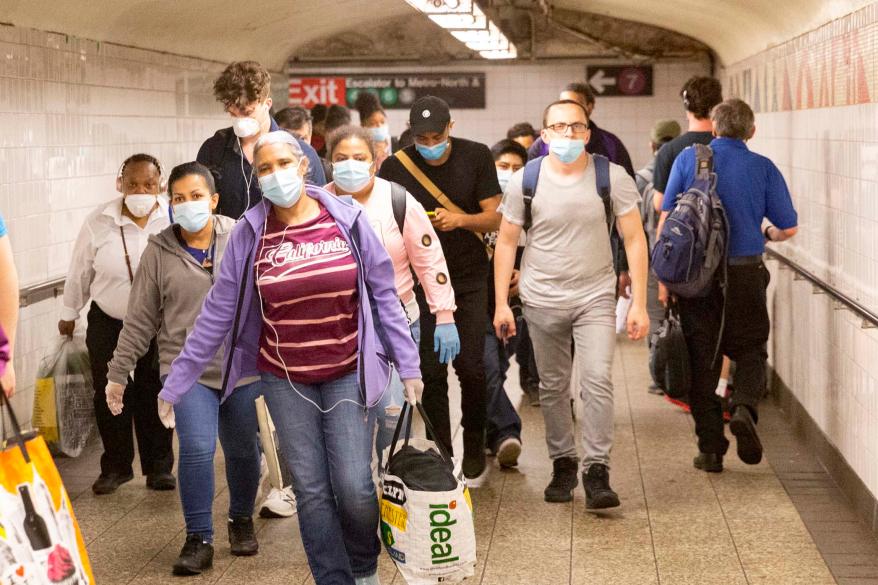 A crowd of straphangers wearing masks coming from the 7 train at Grand Central 42nd Street Station in NYC.