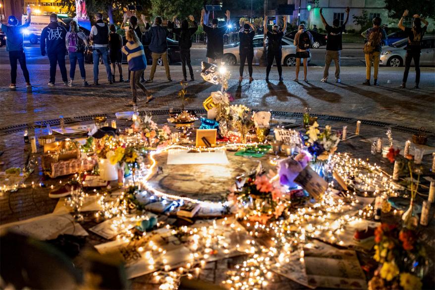 Protesters stand with their hands up in front of a memorial to Breonna Taylor.