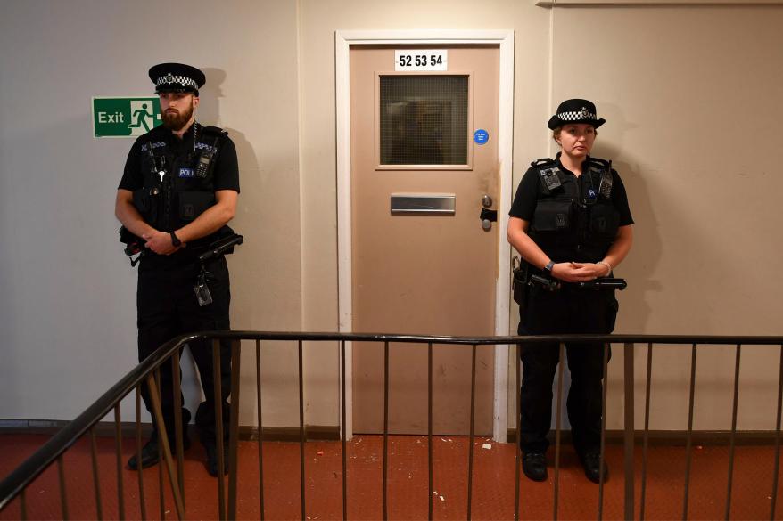 Police officers guarding a doorway in the apartment building where the suspect is believed to have lived.