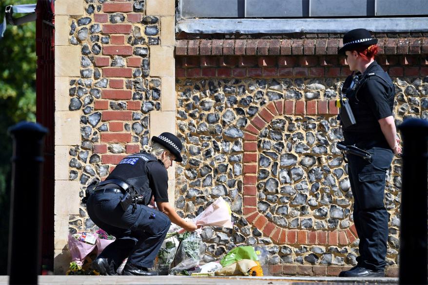 A police officer leaving flowers at the scene of the stabbings in Reading.