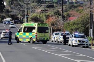 Armed police watch as an ambulance leaves the scene of a shooting incident following a routine traffic stop in Auckland, New Zealand.