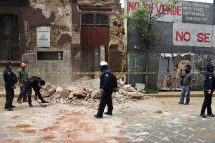A policeman removes rubble from a building damaged by the earthquake in Oaxaca