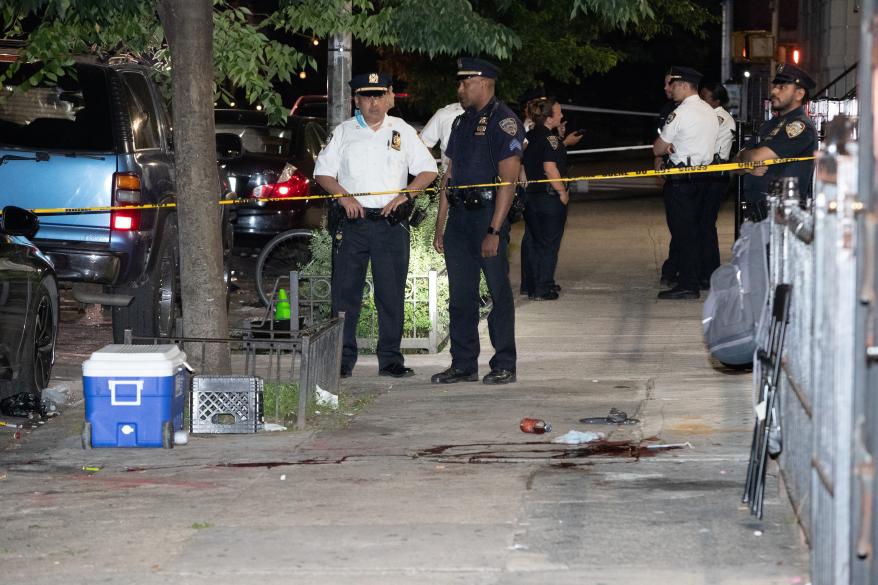 Cops stand next to blood at the scene of a shooting at 225 Bainbridge St. in Brooklyn