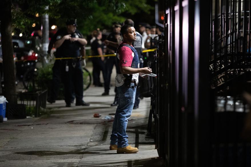 A plain clothes police officer talks to a resident at the scene of a shooting at 225 Bainbridge St. in Brooklyn