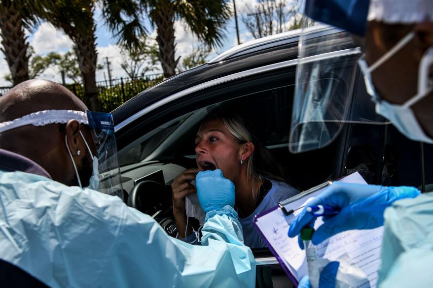 Medical staff take samples from a woman at a drive-thru coronavirus testing site in West Palm Beach, Florida.