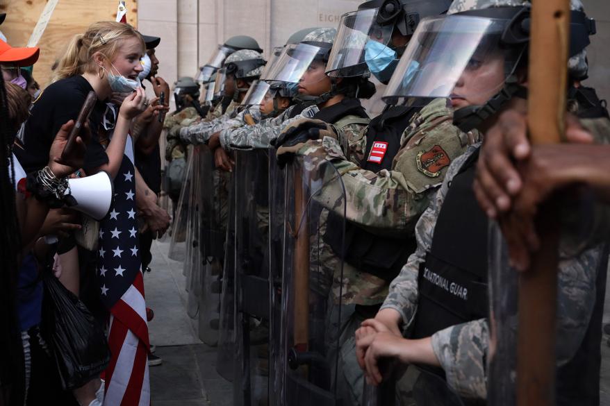 Demonstrators stand in front of D.C. National Guard members.