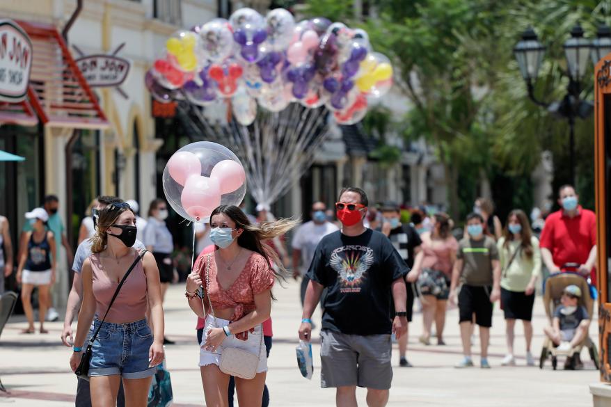 Guests required to wear masks because of the coronavirus pandemic stroll through the Disney Springs shopping, dining and entertainment complex Tuesday in Lake Buena Vista, Florida.