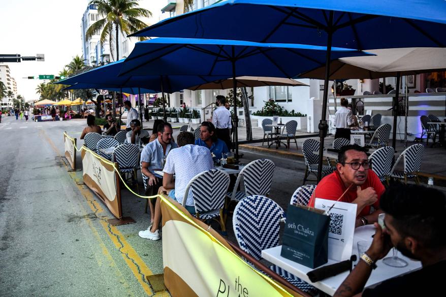 People eat in the outdoor dining area of a restaurant on Ocean Drive in Miami Beach, Florida.