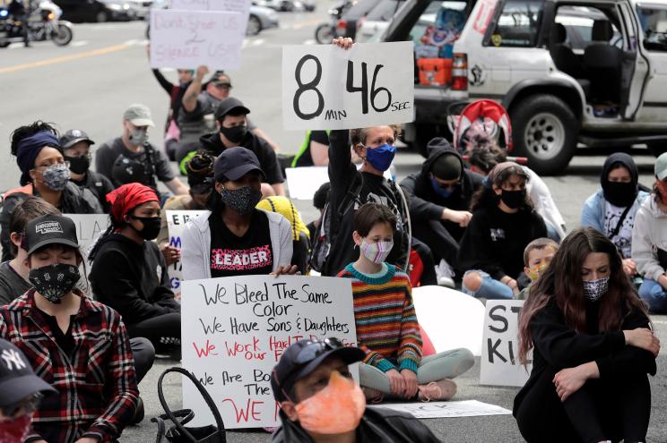 A protester holds a sign that reads "8:46"