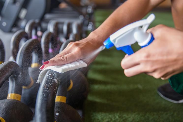 Gym employee spraying kettlebells.