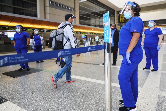 A traveler walks past screeners testing a system of thermal imaging cameras which check body temperatures at Los Angeles International Airport.