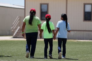 Immigrants seeking asylum hold hands as they leave a cafeteria at the ICE South Texas Family Residential Center in Dilley, Texas.