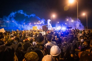 Police officers spray tear gas at protesters by the Crescent City Connection bridge in New Orleans