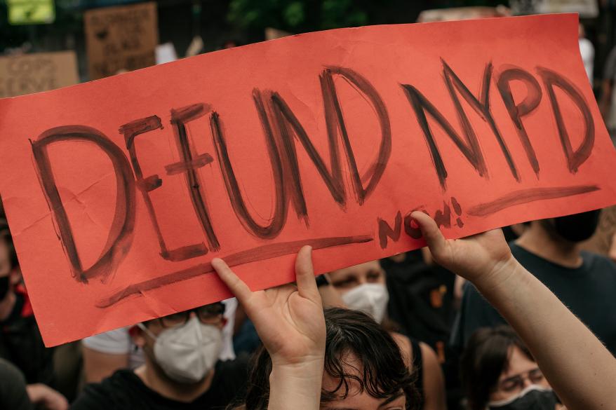 A woman holds a sign calling for the defunding of the NYPD.