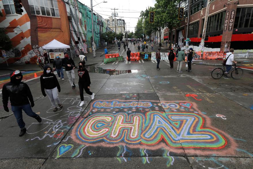 People walk past street art that reads "Welcome to CHAZ."