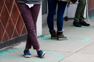 People stand in freshly painted circles, 6 feet apart, as they wait in a two-hour line to buy marijuana products from Good Chemistry on March 23 in Denver.