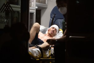 A slashing victim sticks his tongue out as he lies on a stretcher in an ambulance at W 4th and Grove St.