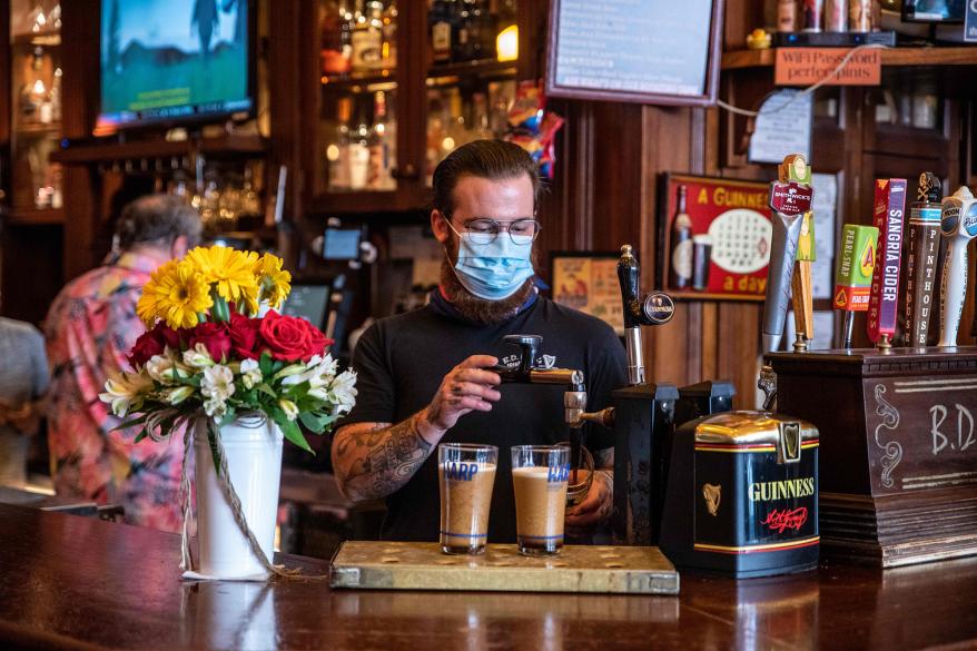 A bartender pours drinks for customers at a bar in Austin, Texas.