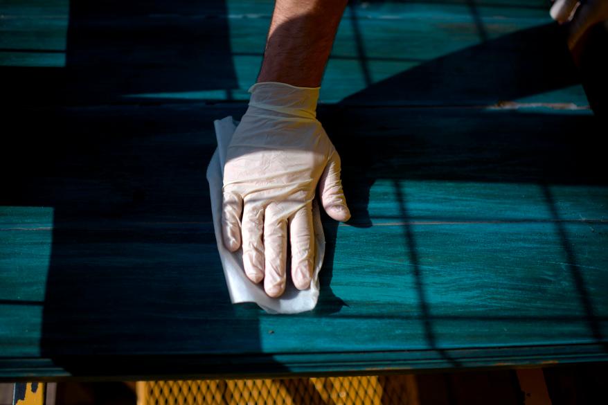 An employee wipes down a patio table at Under the Volcano in Houston, Texas