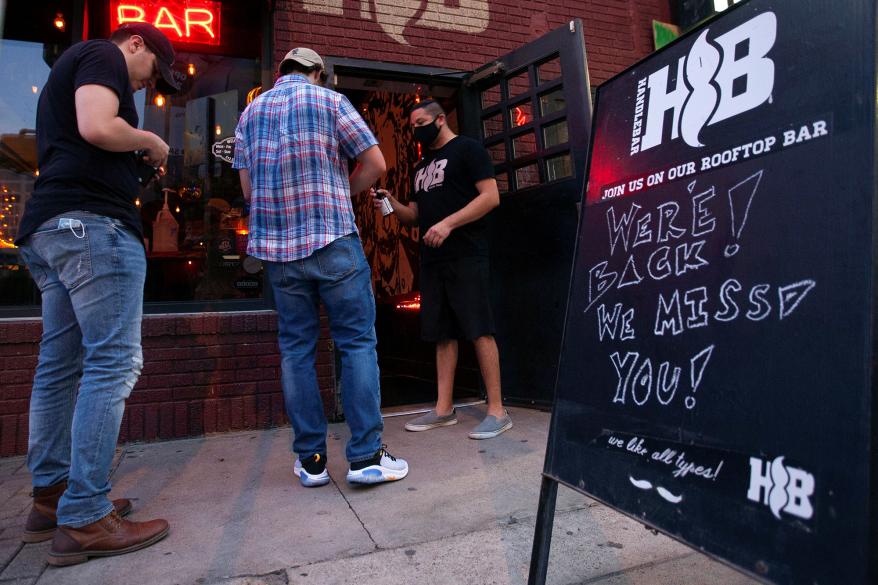 A bouncer sprays down a guest's hands with sanitizer outside of a bar in Austin, Texas.