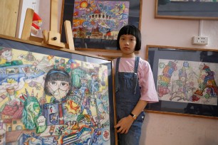 Nguyen Doi Chung Anh, 10, a Vietnamese school girl stands next to her paintings about the coronavirus disease (COVID-19) at home in Hanoi, Vietnam.