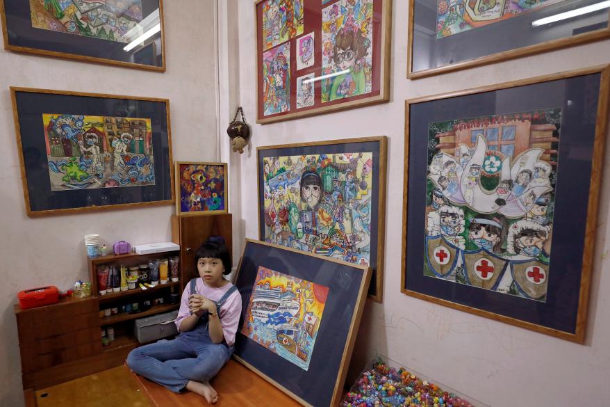 Nguyen Doi Chung Anh, 10, a Vietnamese school girl sits next to her paintings about the coronavirus disease (COVID-19) at home in Hanoi, Vietnam.