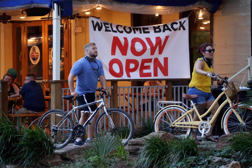 Visitors to the River Walk pass a restaurant that has reopened in San Antonio, Wednesday, May 27, 2020