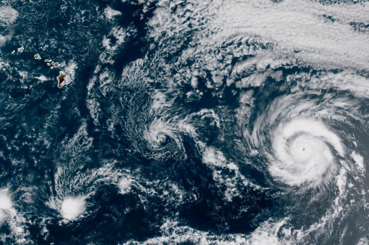 Hurricane Douglas (right) churning in the Pacific Ocean heading toward Hawaii (left).