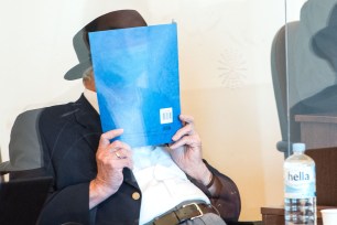 Bruno Dey, a former SS-watchman at the Stutthof concentration camp, hides his face behind a folder next to his lawyer Stefan Waterkamp at the start of a hearing.